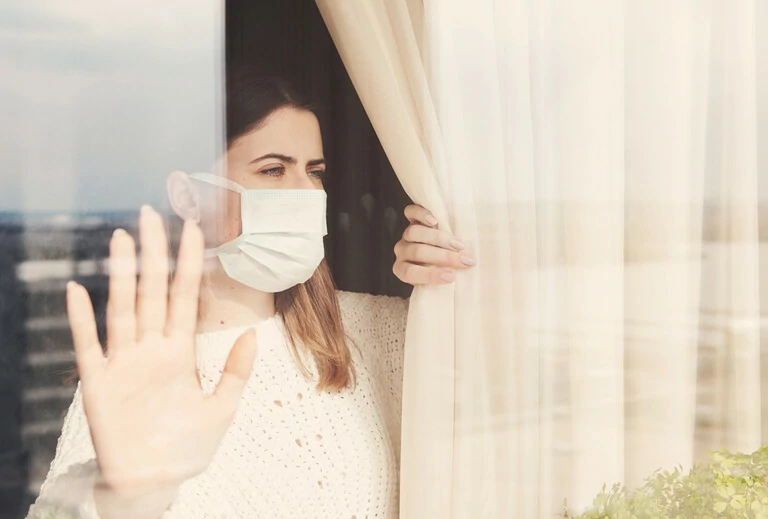 Une jeune femme portant un masque médical reste à la maison pour s'isoler. Concept de quarantaine d'incendie domestique, prévention COVID-19